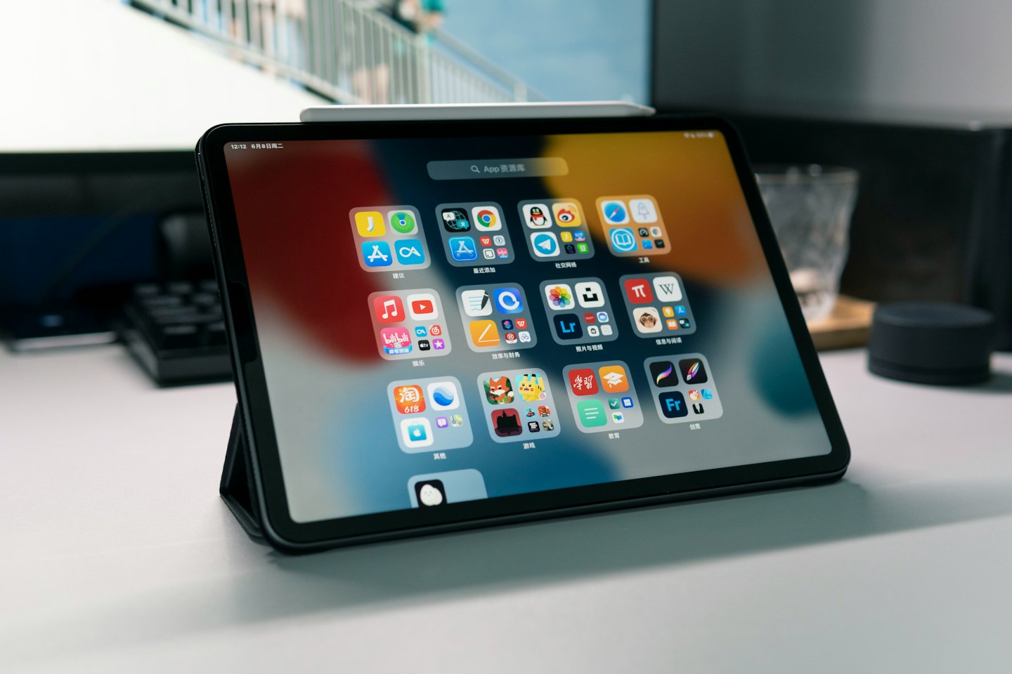 Tablet dengan ikon aplikasi berwarna-warni diletakkan di atas meja putih.